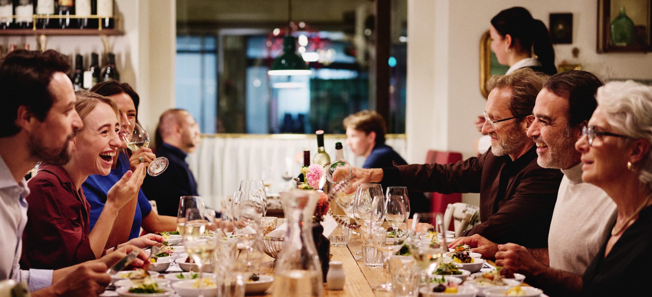 Eine Gruppe von Menschen genießt eine Mahlzeit an einem Tisch im Restaurant.