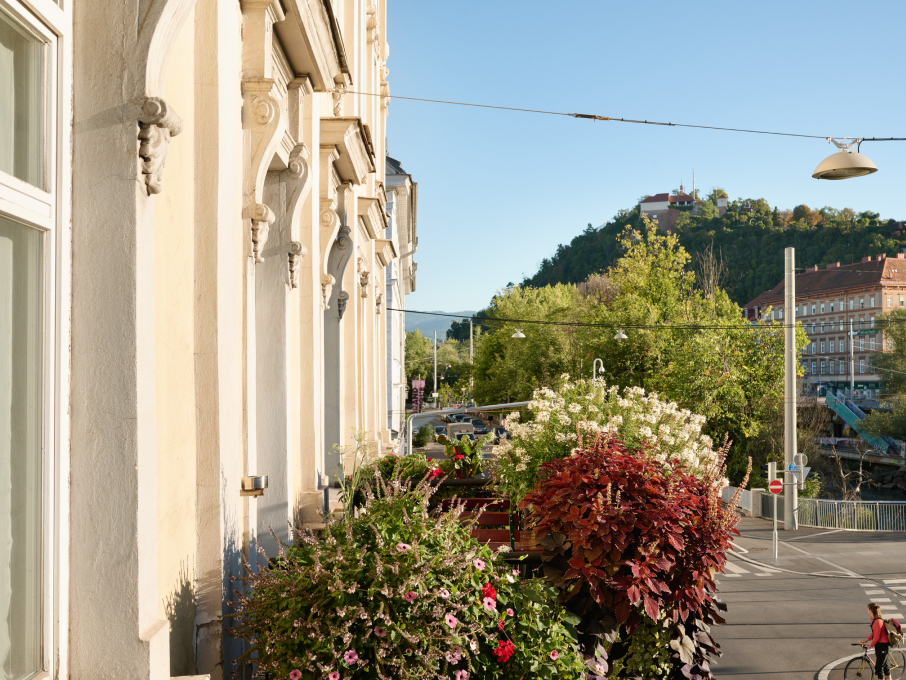 Ein Gebäude mit Blumen mit Blick auf die Stadt Graz und den Schlossberg in Österreich.