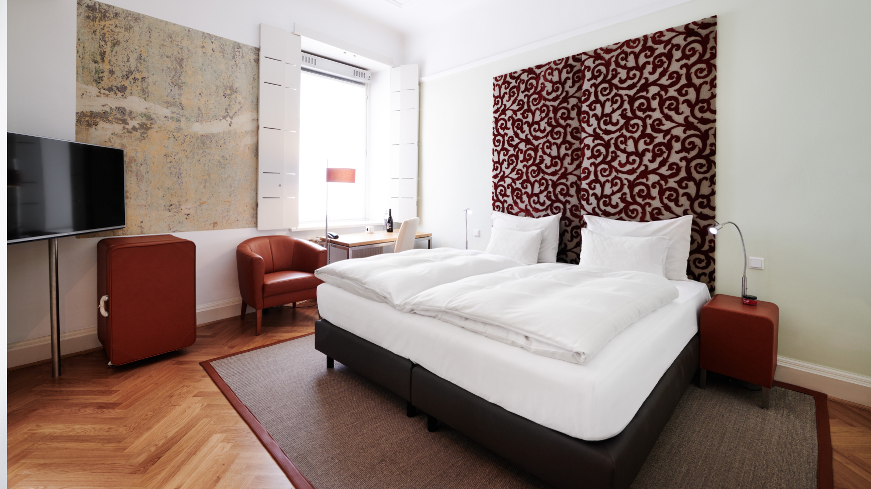 Ein Hotelzimmer mit einem Doppelbett, einem Schreibtisch und einem Fernseher.