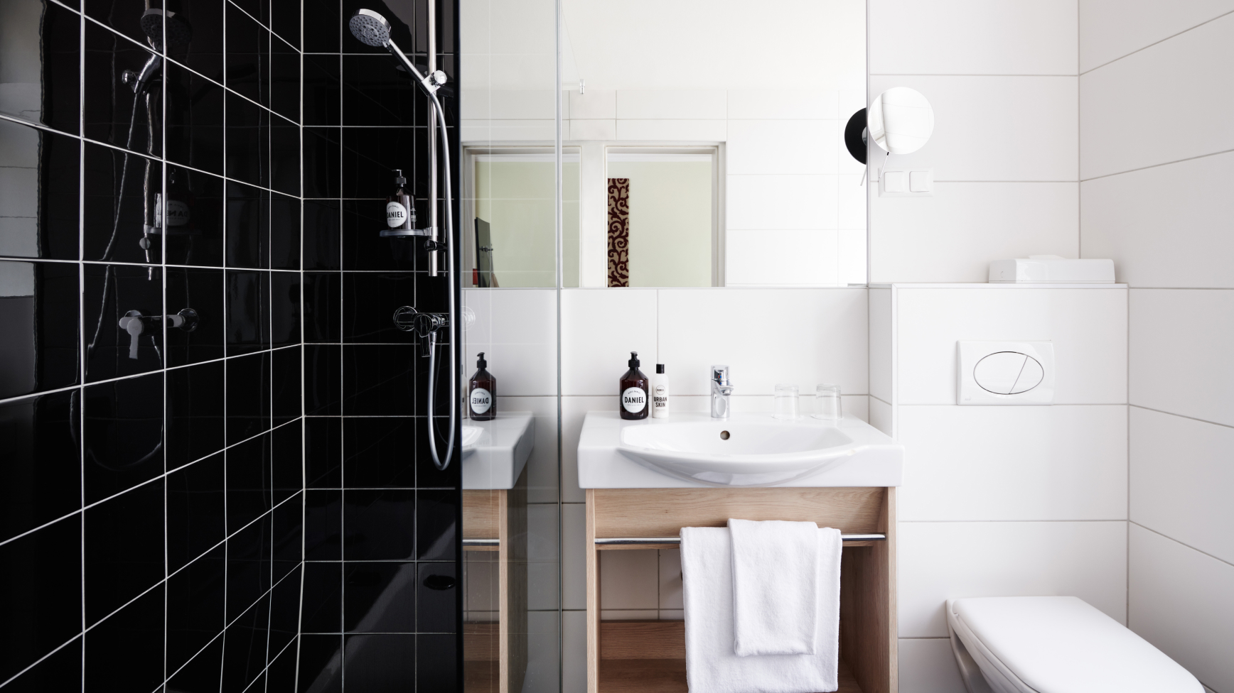 Schwarz-weißes Badezimmer mit Dusche, Waschbecken, Handtüchern und Toilette.