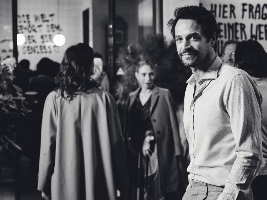 Schwarzweißaufnahme von Glenn Howerton in "BlackBerry". Auf der Wand steht Text.