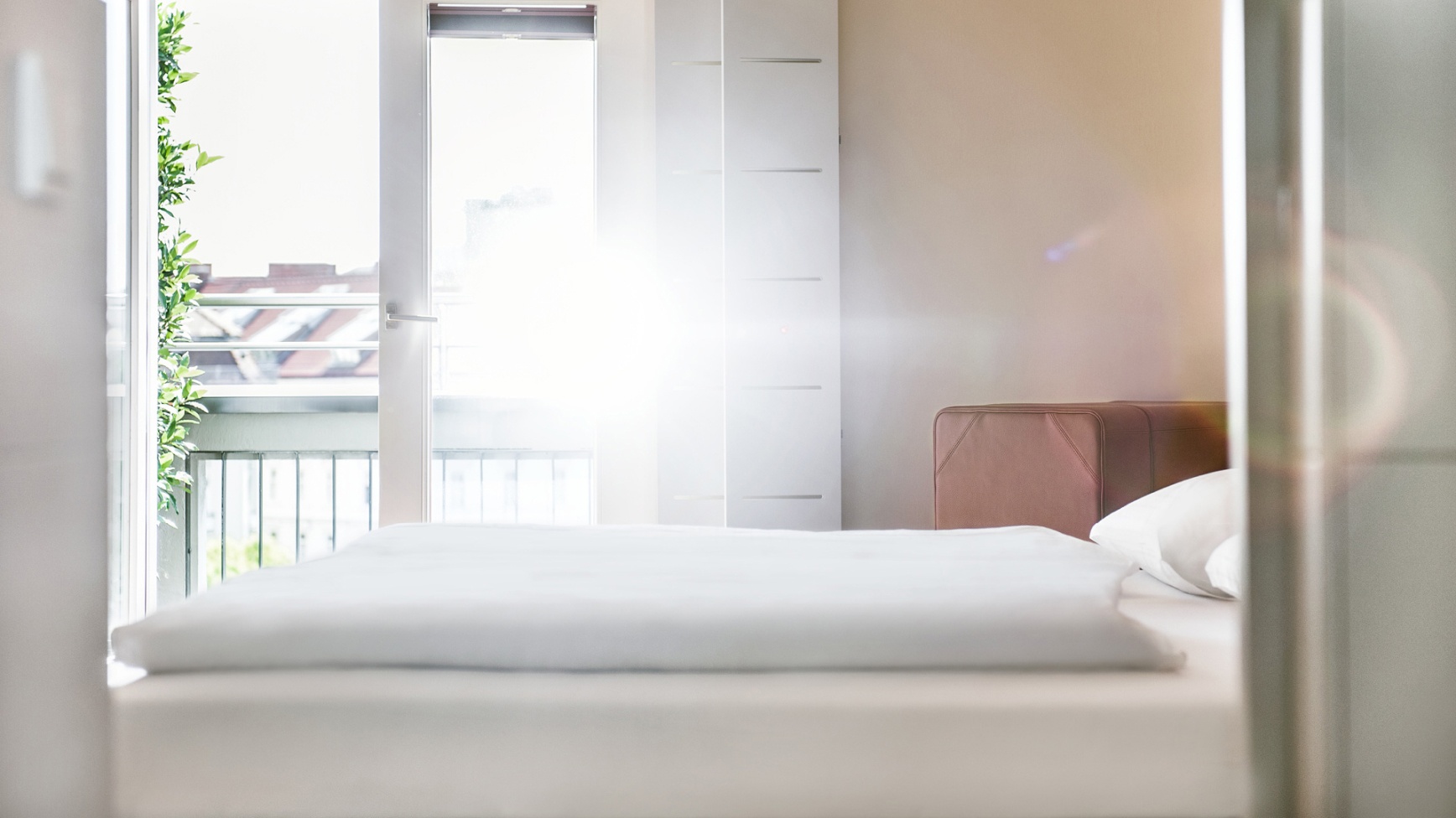 Helles Schlafzimmer mit Bett und Balkon, Sonnenschein.