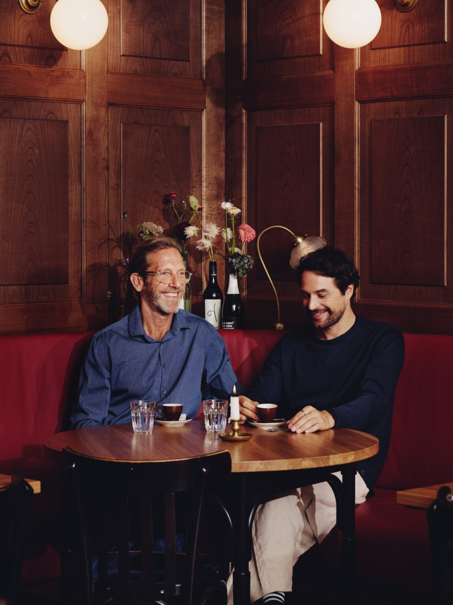 Zwei Männer sitzen an einem Holztisch in einem gemütlichen Restaurant mit Holzvertäfelung.