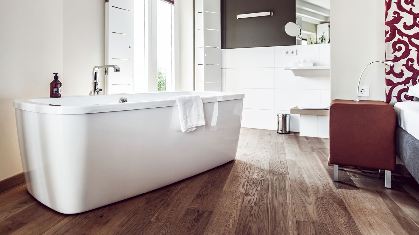 Ein modernes Badezimmer mit freistehender Badewanne, Holzböden und hellen, neutralen Tönen.