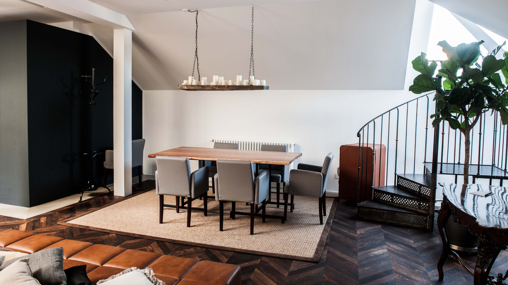 Ein Esszimmer mit Tisch und Stühlen, einem Teppich und einer Wendeltreppe in einem Haus.