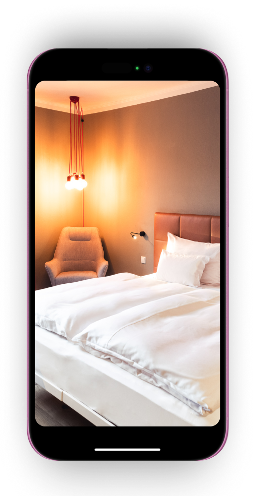 Ansicht des Hotelzimmers auf dem Telefonbildschirm. Doppelbett, Lampe und Sessel sind zu sehen.
