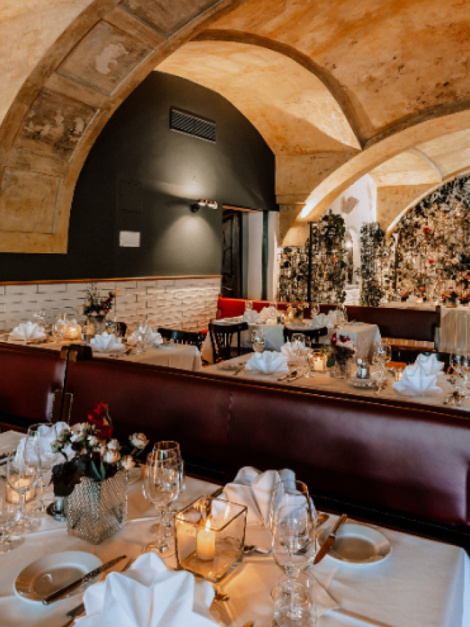 Ein schickes Restaurant mit gewölbter Decke und eingedeckten Tischen mit Blumen und Kerzen.