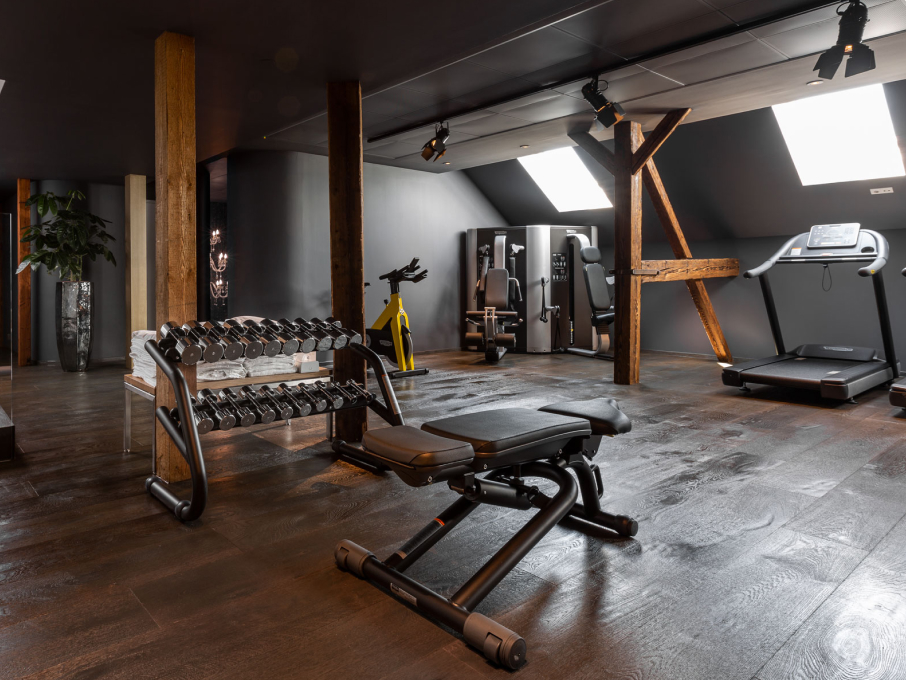 Gym featuring dumbbells, treadmill, training machines, wooden supports, and black ceilings.