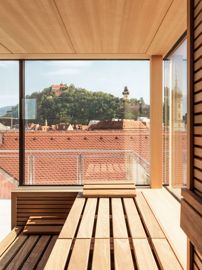 Sauna interior with wooden benches. View of Graz, Austria, including the Schlossberg.