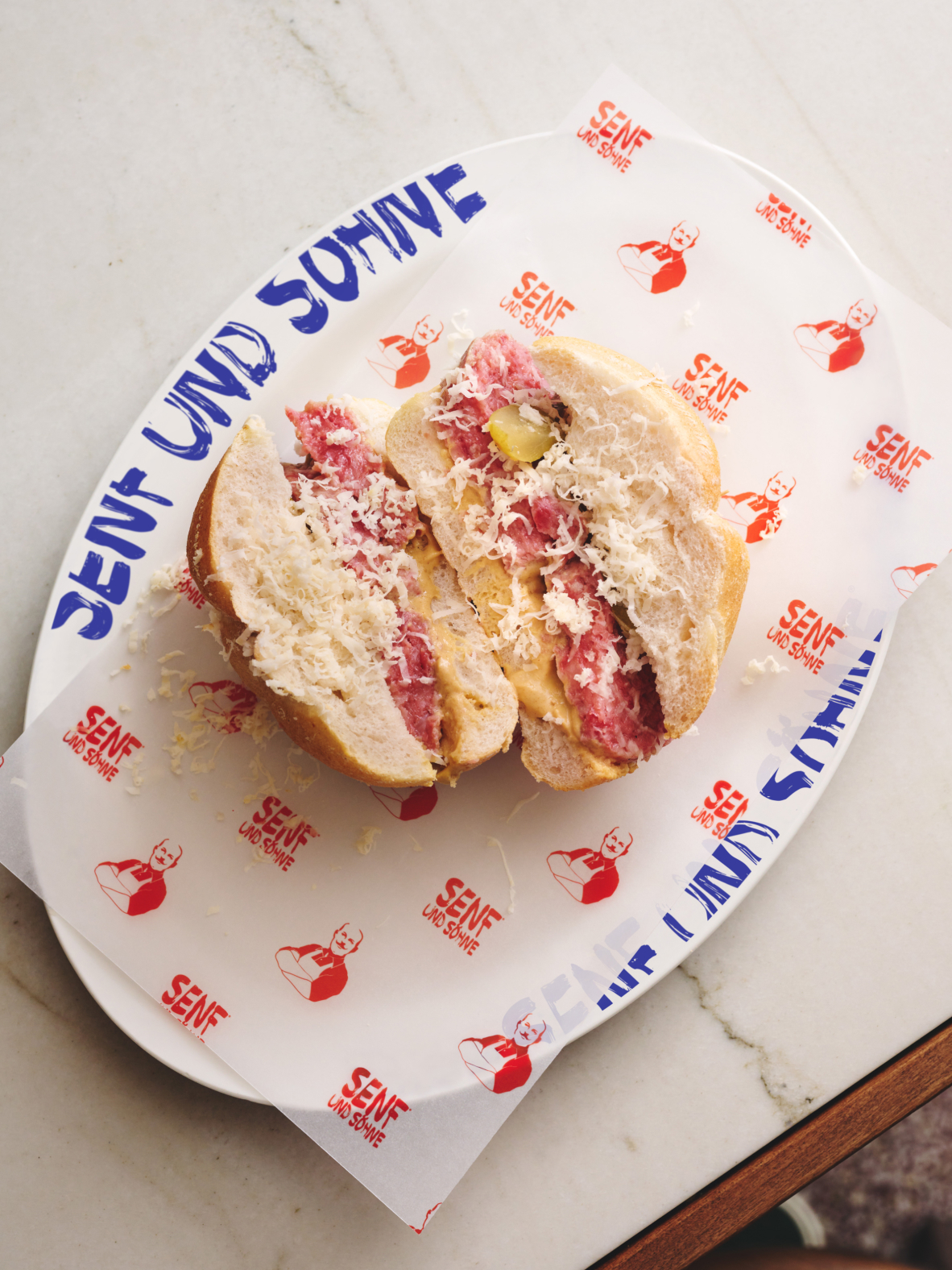 Eine aufgeschnittene Steira Semmel, serviert auf einem Teller mit dem Text "Senf und Söhne".